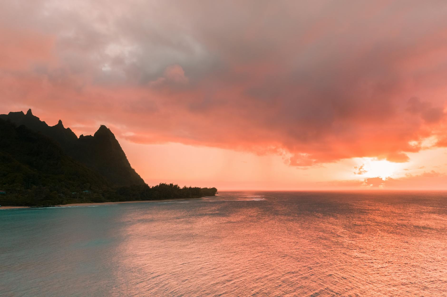 silhouette of mountain beside body of water during sunset
