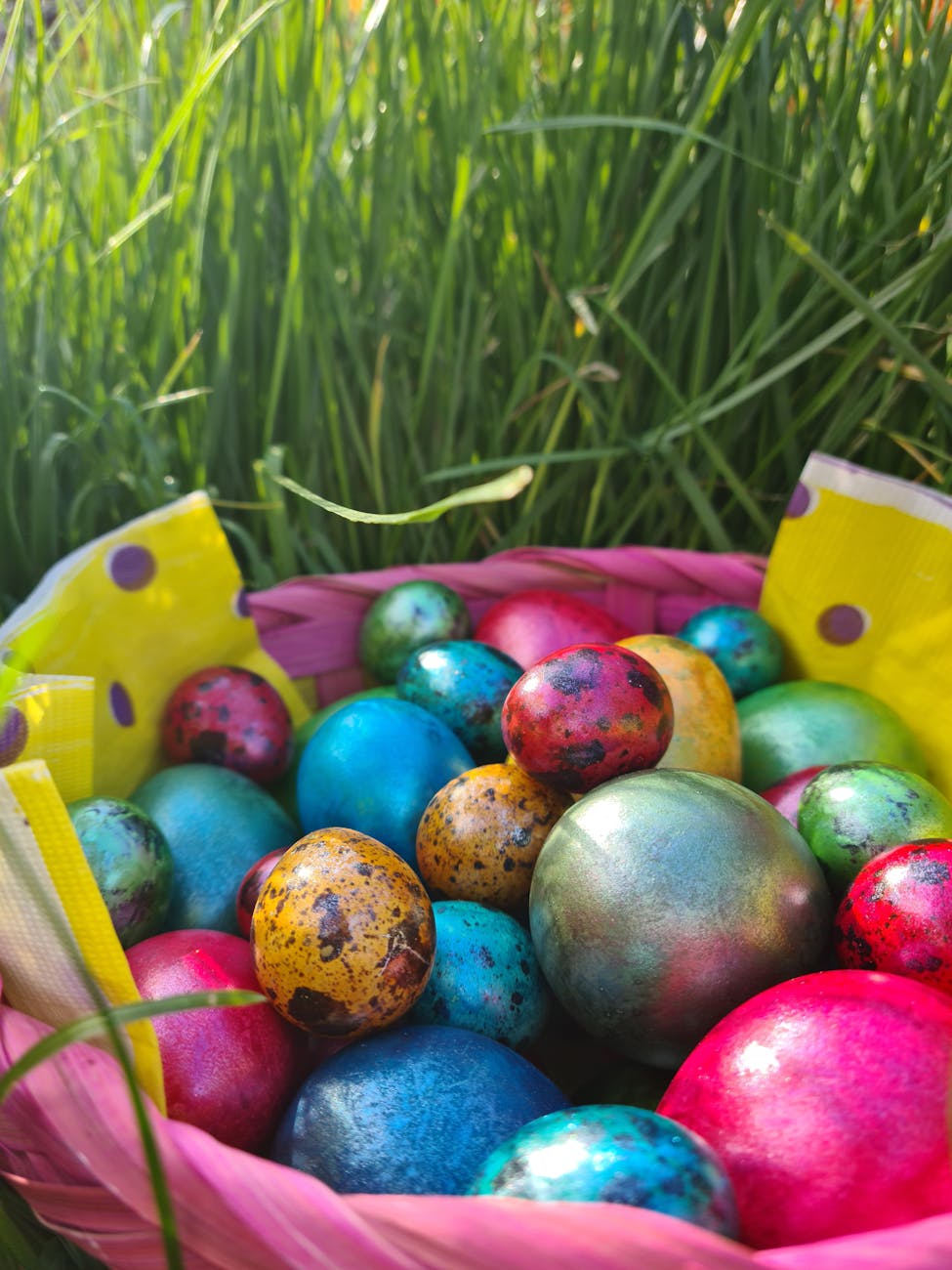 basket with colorful easter eggs standing in grass